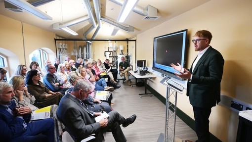 A man talking to guests and standing in a room