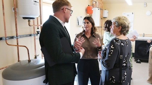 A group of people talking in front of some sustainable heating equipment.