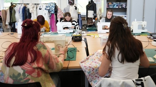 The group working on a large desk space with sewing machines