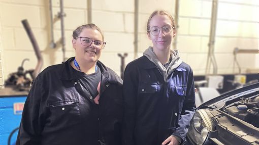 Lily and Sophie standing next to each other in the motor vehicle workshop
