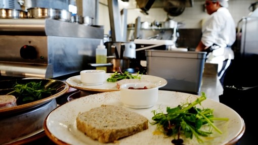 A dish in the foreground a starter pate dish with the kitchen blurred in the back