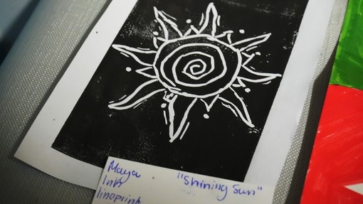 A picture of a print in a book, black background, white outline of a sun graphic