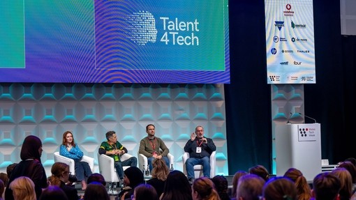 People talking on stage in a panel with an audience