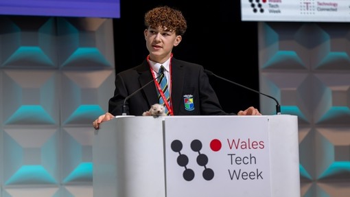 A person in school uniform talking on stage with Wales Tech Week as a brand on the lectern