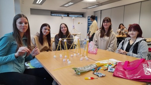 A group of students around a desk building structures from spaghetti and marshmallows