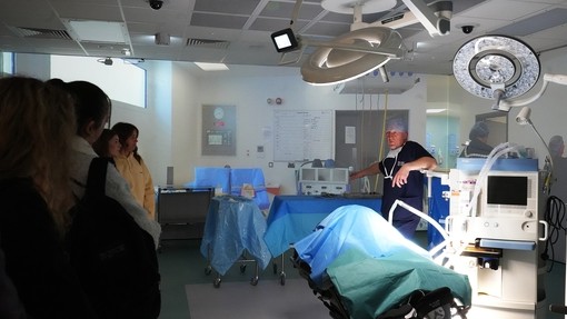 Students in the operating theatre training area with a man dressed in scrubs and mask