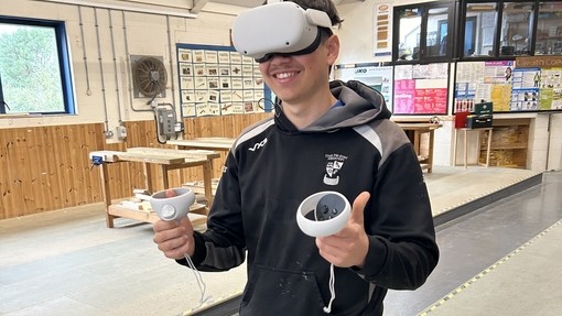 A carpentry student in work clothes wearing a VR set