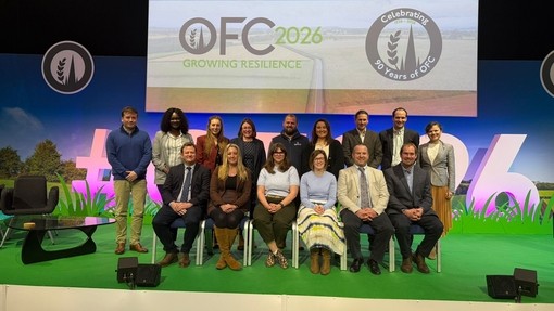 The whole group (15) seated on a stage