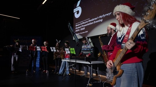Someone playing the guitar in the foreground wearing a Xmas hat
