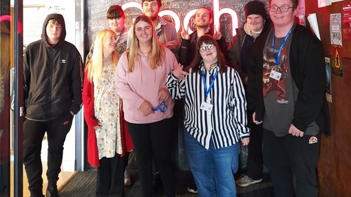 Students standing in a group by the Arad Goch sign which are illuminated letters