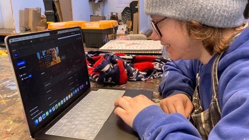 An art student looking closely at their laptop