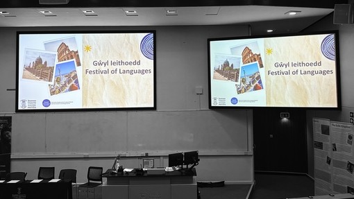 A picture of two overhead screens at the university saying Festival of Languages