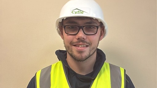 Matthew Thomas in a white hard hat and hi-vis jacket looking at the camera