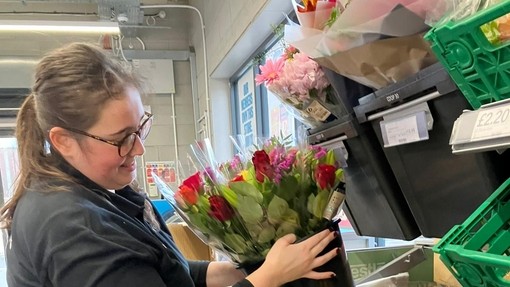 Nia in her coop uniform tidying some flowers 