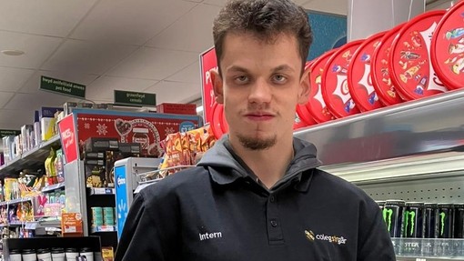 Regan in the store by a fridge holding some juice bottles 