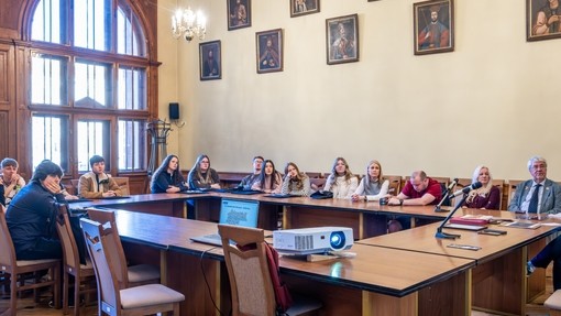 Students in a large official room around a table in Poland