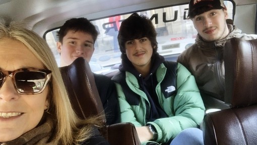 Three students in the back of a car having a selfie with their tutor Carolann in the front