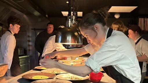 Students at the pass, plating up food with low lighting  