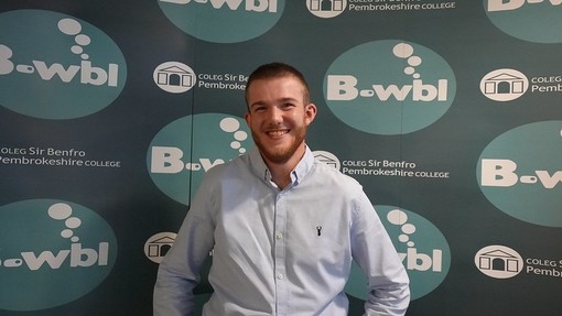 Harry in a shirt standing in front of Bwbl branding big smile
