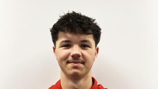 Noah in a red branded top looking at the camera