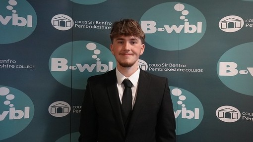 Sean in a suit standing in front of Bwbl branding