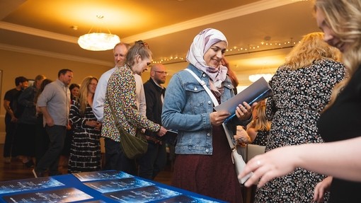 A crowd gathering for the awards focussed on the table where they pick up the awards brochure