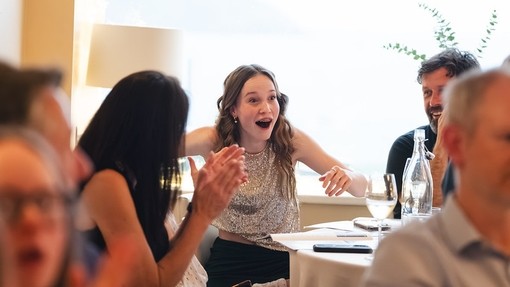 A student looking really shocked at her name being called on a table with other people