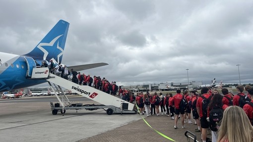 All the students queuing up to get on the plane in their red kit