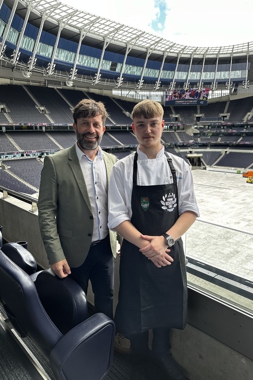 Oliver standing in a stadium with his lecturer