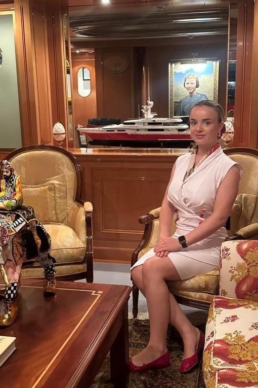 Female student in uniform sat on a chair in a yacht she works on
