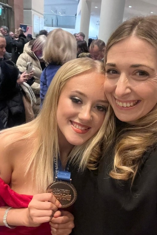 A student leans into another lady with her medal