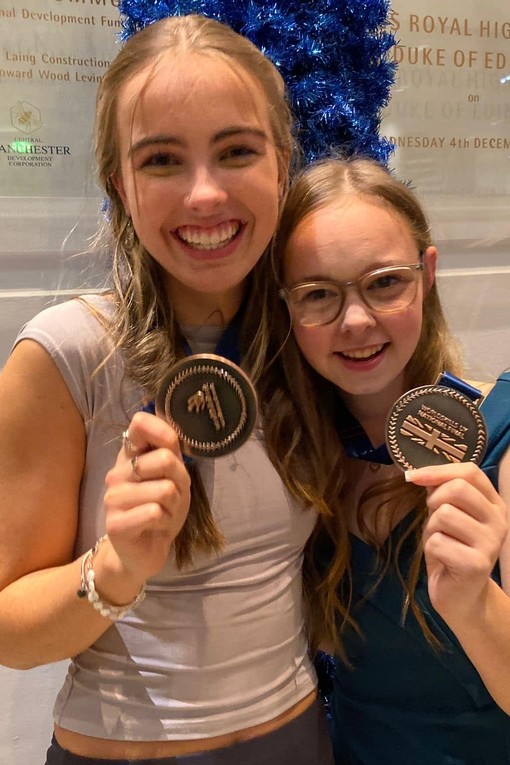 two female students holding their medals and hugging