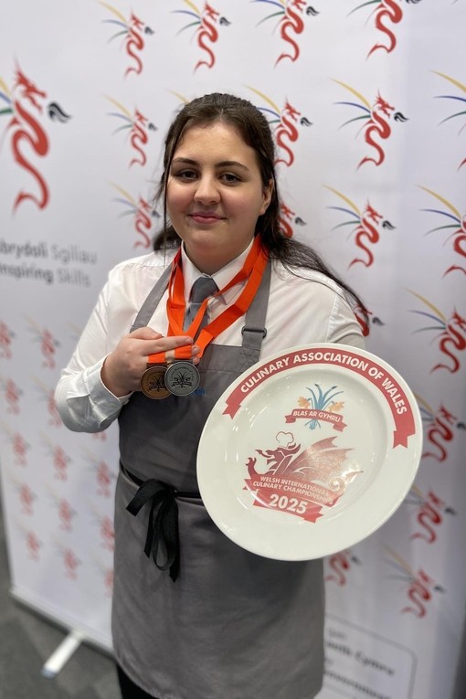 Angharad standing in front of Inspiring Skills branded background holding her medal