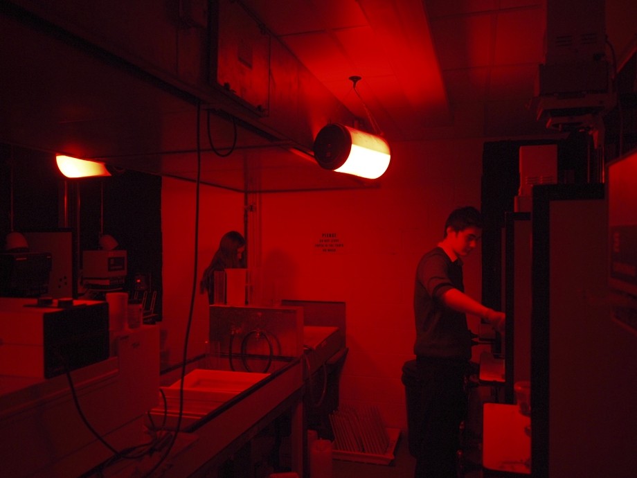 Students develop photos in a dark room. 