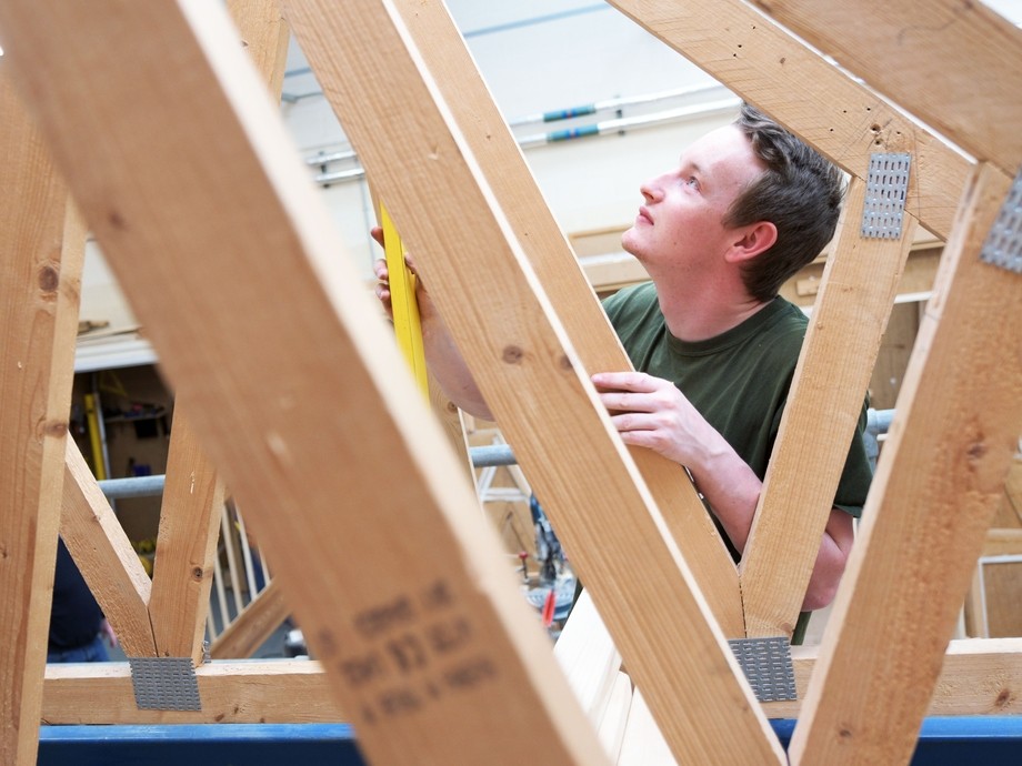 Construction student measuring a timber frame.