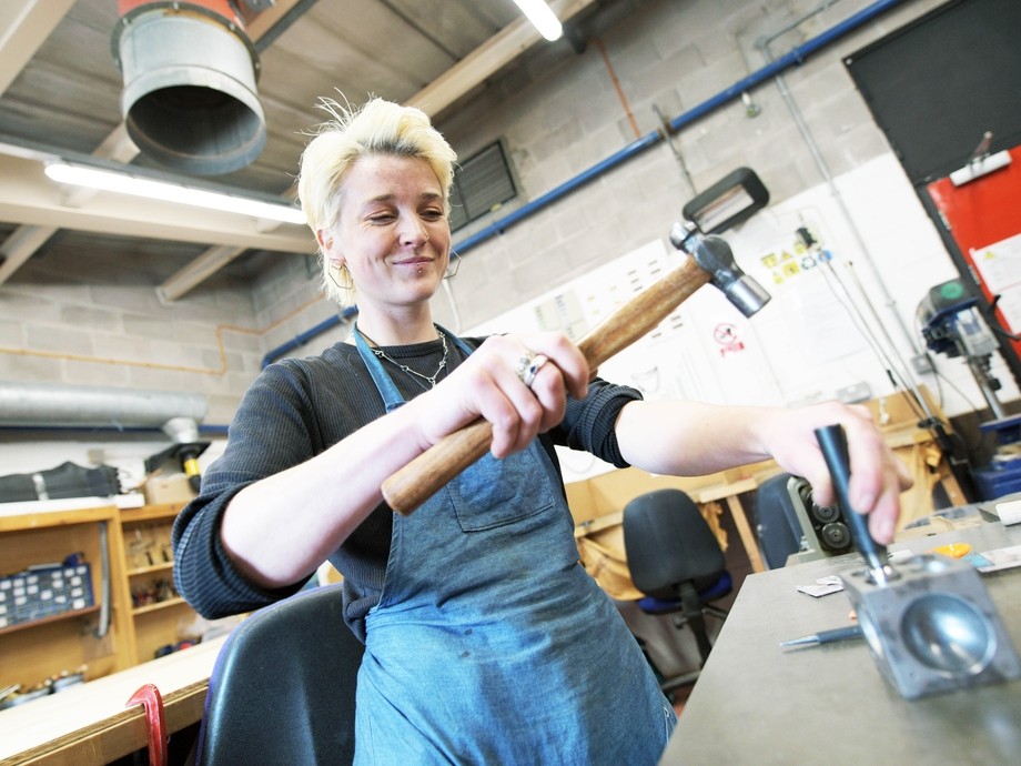 A student hammers some jewellery into shape.