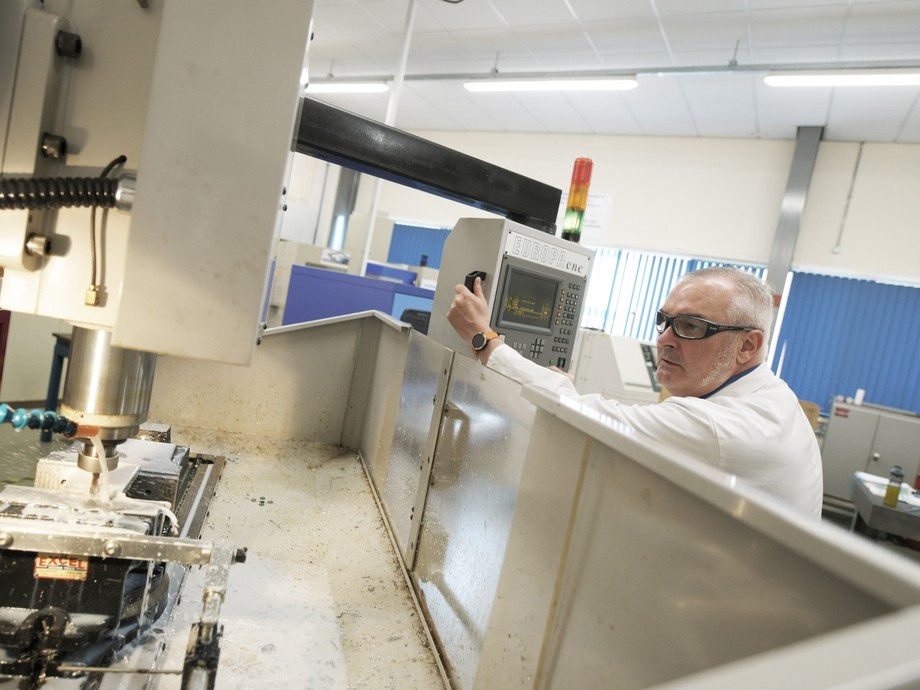 A lecturer programs a cutting machine.