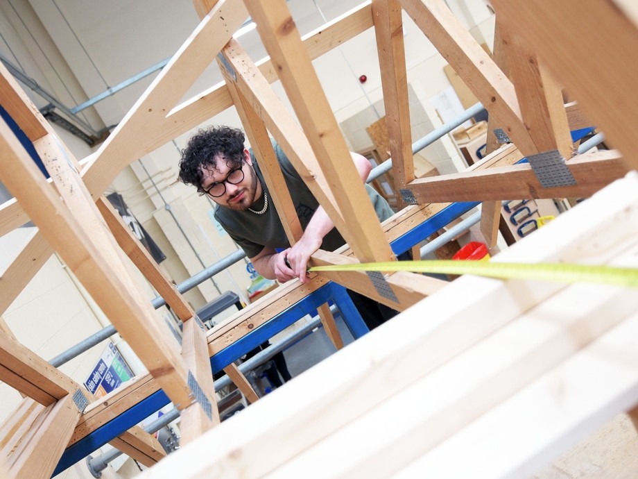 A student measuring a wooden frame.