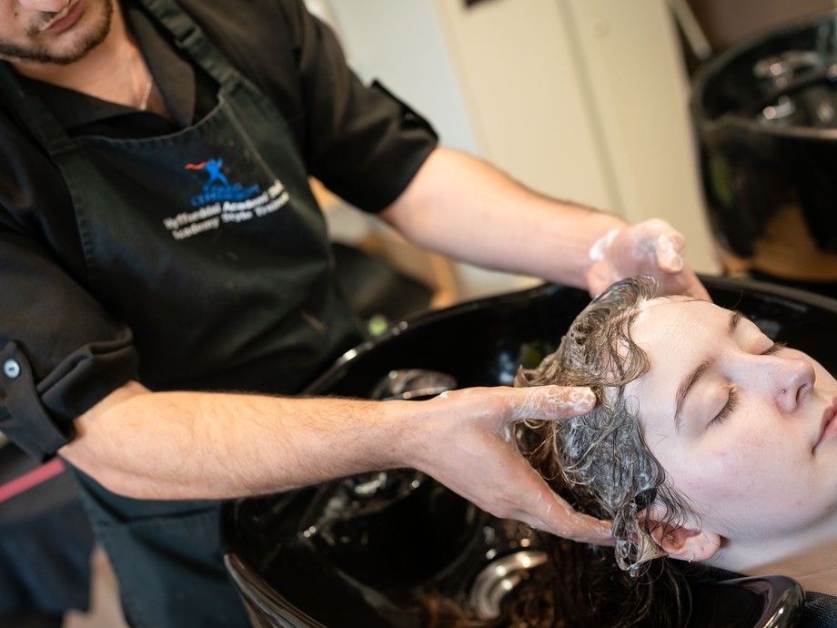 student at basin washing clients hair