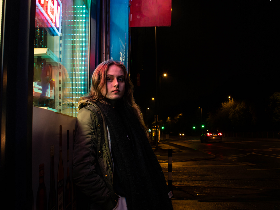 Poppy's album cover which is her standing in the dark under neon sign and window 