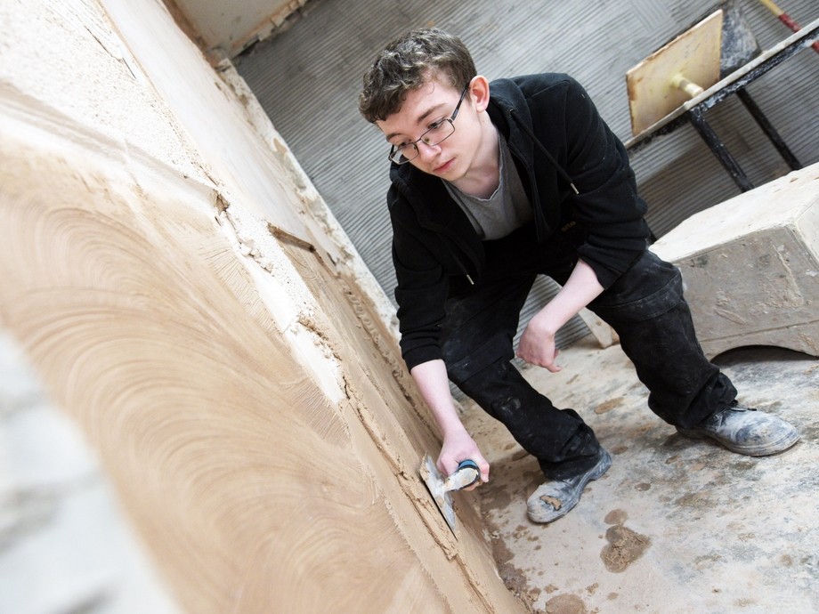 Student plastering wall