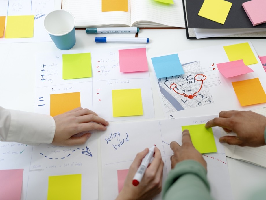 People brainstorming ideas through post it notes on table