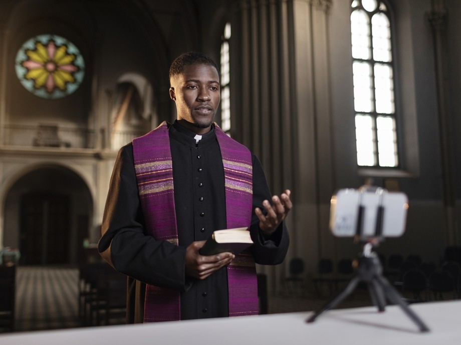 Priest in church recording on phone