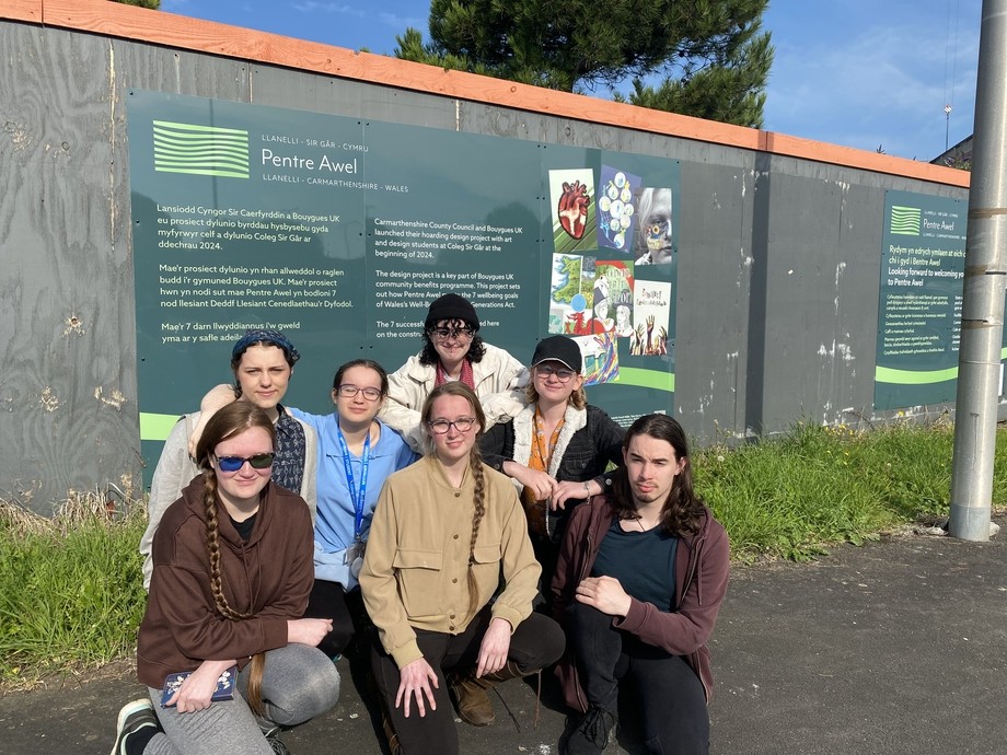 A group of students outside the site in front of the hoardings which show their designs