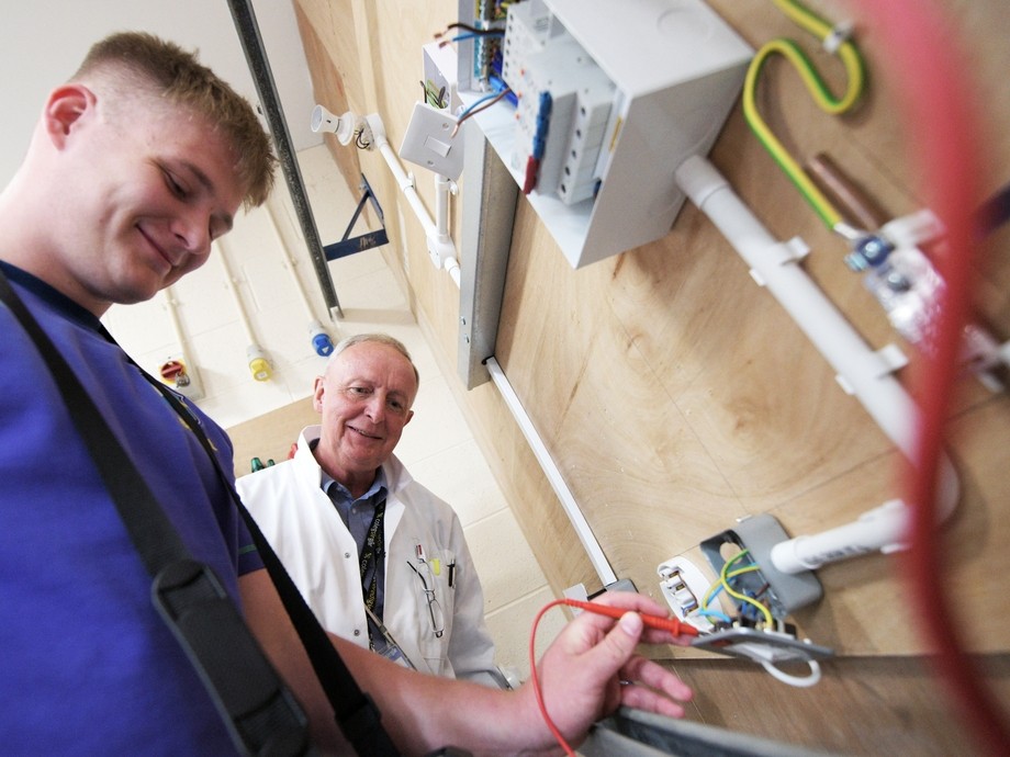 Lecturer watching a student practice electrical installation