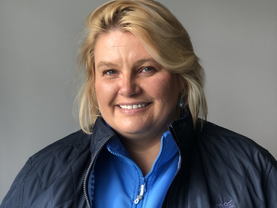 Olga in a blue top and coat in a headshot