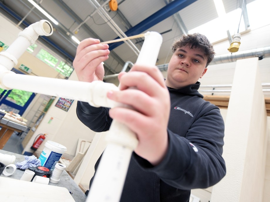 Plumbing student practicing with white plastic pipes