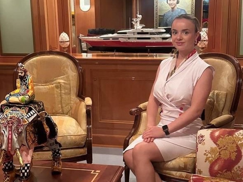 Female student in uniform sat on a chair in a yacht she works on