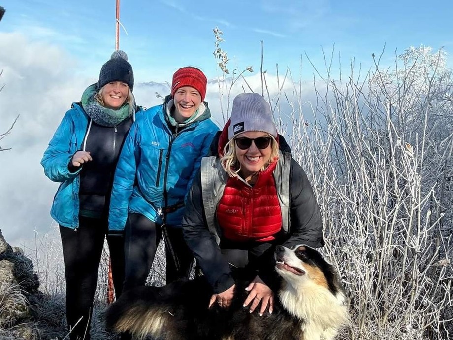 Three people dressed for the cold in a cold environment with a dog