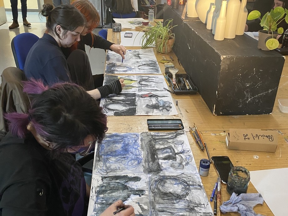 Three female students focus on their art projects, each expressing creativity in a lively and inspiring environment